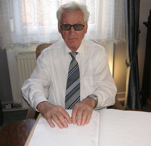 Leonhard Rupflin liest in einem Buch, welches in Braille geschrieben ist.